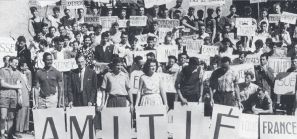 Large group of people holding signs with the word 'AMITIÉ' (friendship) in a public gathering